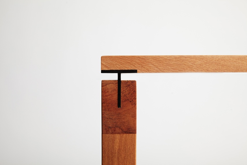 The desk features sharp negative detailing around the edges and flush pin joints through the feet.